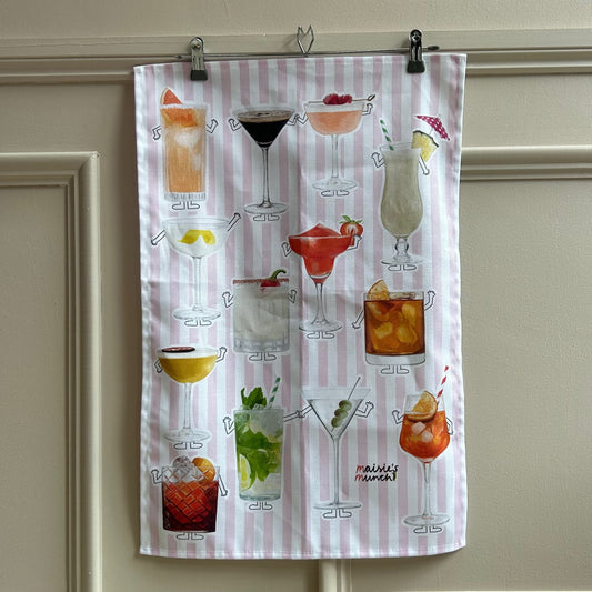 Cocktails tea towel with pink stripes hanging on a panelled wall