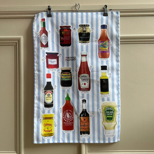 Condiments tea towel hanging on a panelled wall